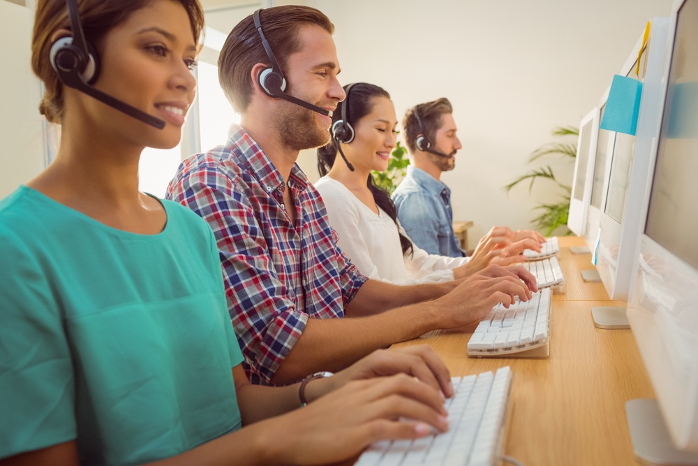 Business team working together at a call centre wearing headsets